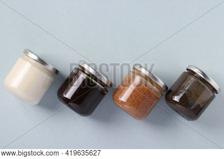 Vegan Organic Paste Of Flax Seeds, Milk Thistle, Peanuts And Coconut In Glass Jars On Light Blue Bac