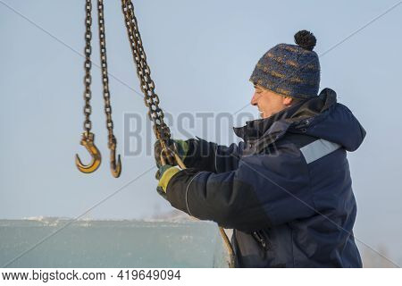 Fitter In A Blue Jacket Works With A Chain Metal Sling