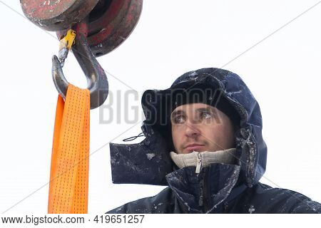 A Portrait Of A Fitter In A Blue Jacket At The Hook Of A Truck Crane