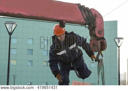 A Portrait Of A Fitter In A Blue Jacket At The Hook Of A Truck Crane