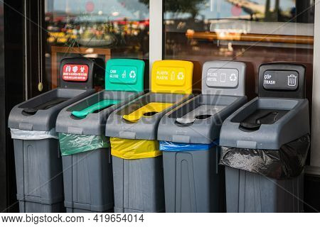 There Are Five Trash Cans On The Street: Red For Masks, Green For Glass, Yellow For Plastic And Pack