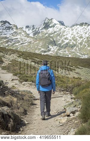 Person With Backpack Walking Down The Mountain On A Sunny Day