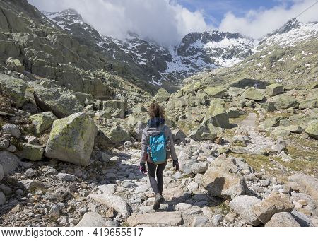 Person With Backpack Walking Down The Mountain On A Sunny Day