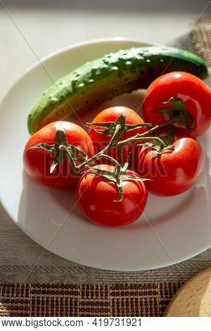 Tomatoes On A Branch And A Cucumber On A White Plate. Backlit Photo. Copspace