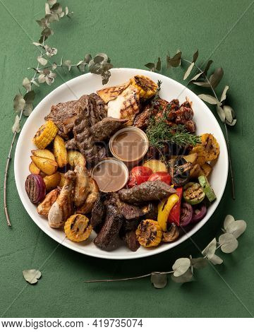 Grilled Meat Platter With Vegetables Isolated On Green Background. Barbecue Concept. Vertical Format