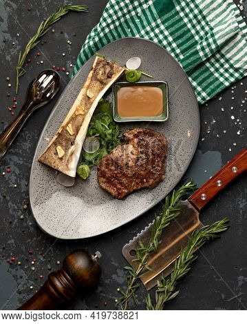 Juicy Fried Meat Fillet And Greens On Black Table With Kitchen Utensils. Top View.