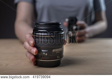 Photographer Showing Camera Lens, Blurred Vintage Old One And Modern 85 Mm Lens In Focus