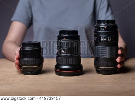 Different Camera Lenses On Wooden Table. 85 Mm, 35 Mm And 300 Mm. Various Modern Digital Lenses Of D