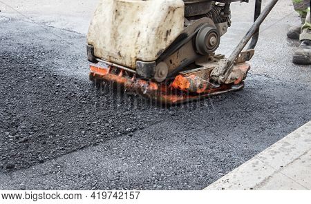 Worker Ramps The Asphalt On The Road With A Mechanical Rammer. Laying The Road Surface. Hot Asphalt 