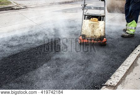 Worker Ramps The Asphalt On The Road With A Mechanical Rammer. Laying The Road Surface. Hot Asphalt 