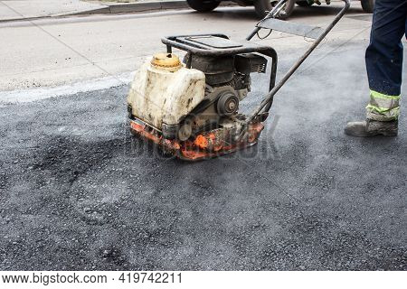 Worker Ramps The Asphalt On The Road With A Mechanical Rammer. Laying The Road Surface. Hot Asphalt 