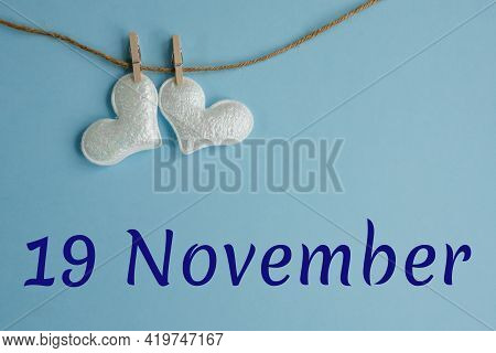 Commemorative Date November 19 On Blue Background With White Hearts With Clothespins, Flat Lay. Holi