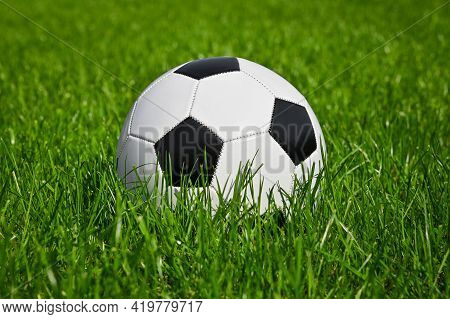 Close Up One Black And White Football Ball In Green Grass Of Soccer Turf Field Pitch, Low Angle, Sid