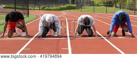 Front View Of Four High School Boys Sprinters Ready On Their Mark To Run A Sprint Race Against Each 