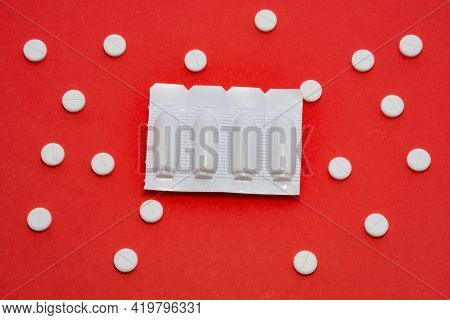 Plastic Packaging With Vaginal Or Rectal Suppositories Is On Redbackground Surrounded By Round Table