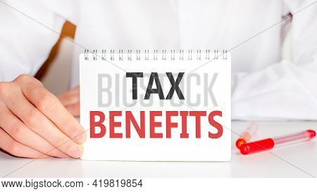 A Sheet Of Paper With Text Tax Benefits, Multicolored Markers On A White Table. Business And Educati