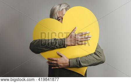 Love Yourself Concept. Happy Person Embracing Self, Hugging A Big Heart. Looking Into Camera. Positi