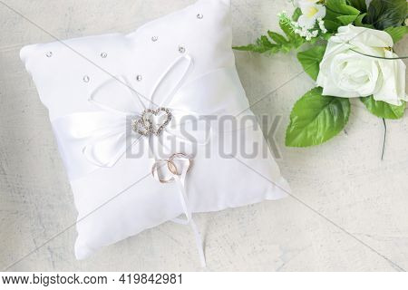 Empty White Pillow For Wedding Rings With Rhinestone Hearts On A Wooden Background. Soft Focus