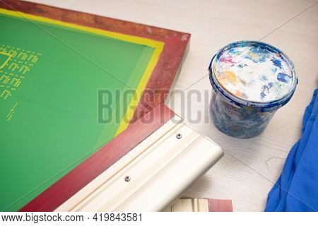 Serigraphy Silk Screen Print Process At Clothes Factory. Frame Template Stencil, Squeegee And Plasti