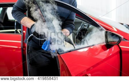 Car Service Worker Cleans Interiror With Steam Cleaner