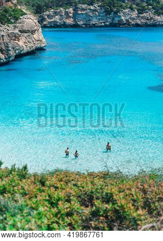 Mallorca, Spain: May 22, 2018: Calo Del Moro Beach, Santanyi.three Persons Standing In Clear Turquoi