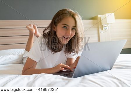 Asian Woman Lying Down And Smiling The Bed And Laptop