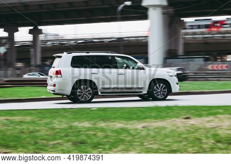 White Suv Car Toyota Land Cruiser 200 At The City Driveway. Auto Moving At High Speed On The Street.