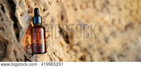 Amber Glass Spray Bottle With White Blank Label On Rock Stone On Beige Background. Natural Organic C