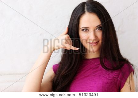 Young Woman making a call me sign outdoors 