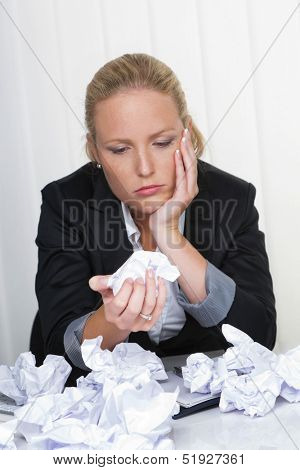 a young woman desperately in office between many file folders and crumpled papier.symbolfoto for stress, burnout and overwork.