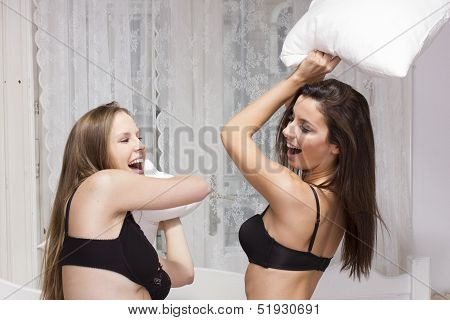 Two sexy girls having pillow fight in the bedroom