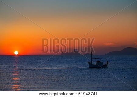 Ibiza sunset Es Vedra view and menorquina fisherboat from Formentera orange sky