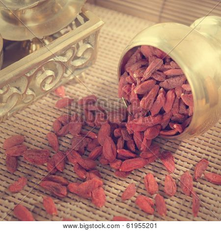 Vintage retra style red dried goji berries, wolfberry or lycium, chinese herbal medicine close-up on bamboo mat. Lycium barbarum.
