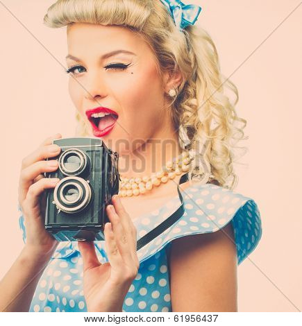 Blond coquette pin up style young woman in blue dress with vintage camera 