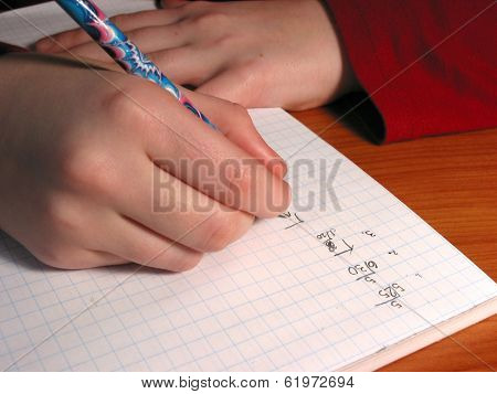 Closeup on the hands of a child doing math homework
