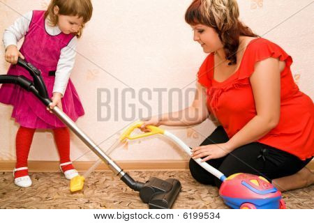 Petite fille et femme aspirer un tapis