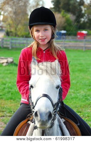 Young girl riding a white pony at countryside