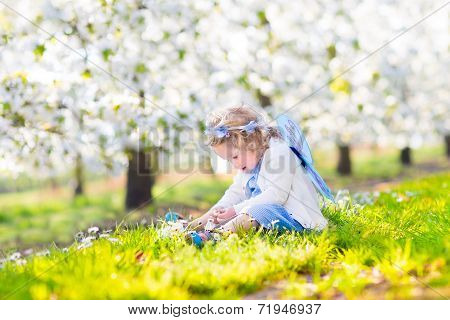 Curly Toddler Girl In Fairy Costume Playing In Fruit Garden