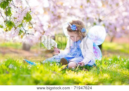 Curly Toddler Girl In Fairy Costume Playing In Fruit Garden