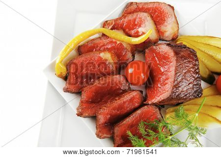 underdone beef meat with vegetables on white plate