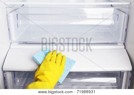 Woman's hand washing refrigerator with duster