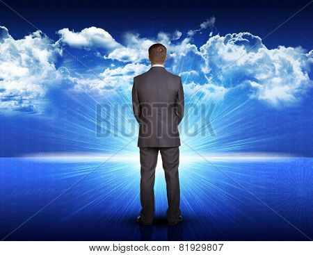 Businessman standing against blue landscape with rising sun