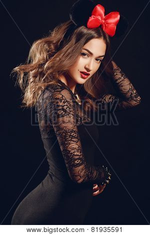 Portrait of a beautiful model with a red bow on a dark background.