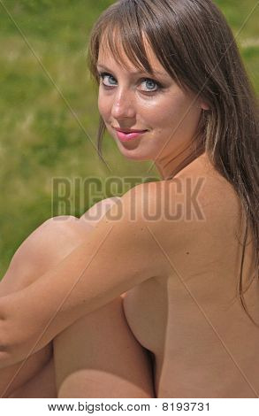 Sorrir sentada nua morena sobre um verde