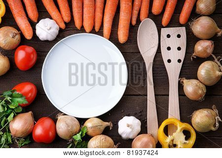 White dish and wooden kitchenware with vegetables on the table