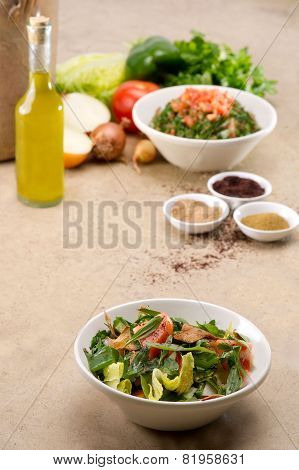 Plates of traditional Arabic salad fattouch and tabbouleh on a rustic background