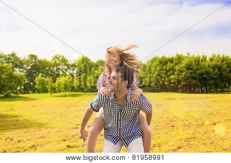Portrait Of Happy Caucasian Couple Playing Outdoors In Summer. Having Fun While Piggybacking And Hap