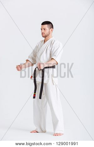 Full length portrait of a man in kimono standing isolated on a white background and loking at camera