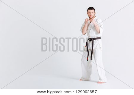 Man in kimono standing in fight stance isolated on a white background