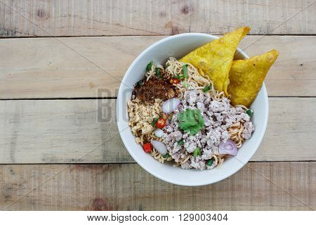 Spicy instant noodle with minced pork on wood background.Topview